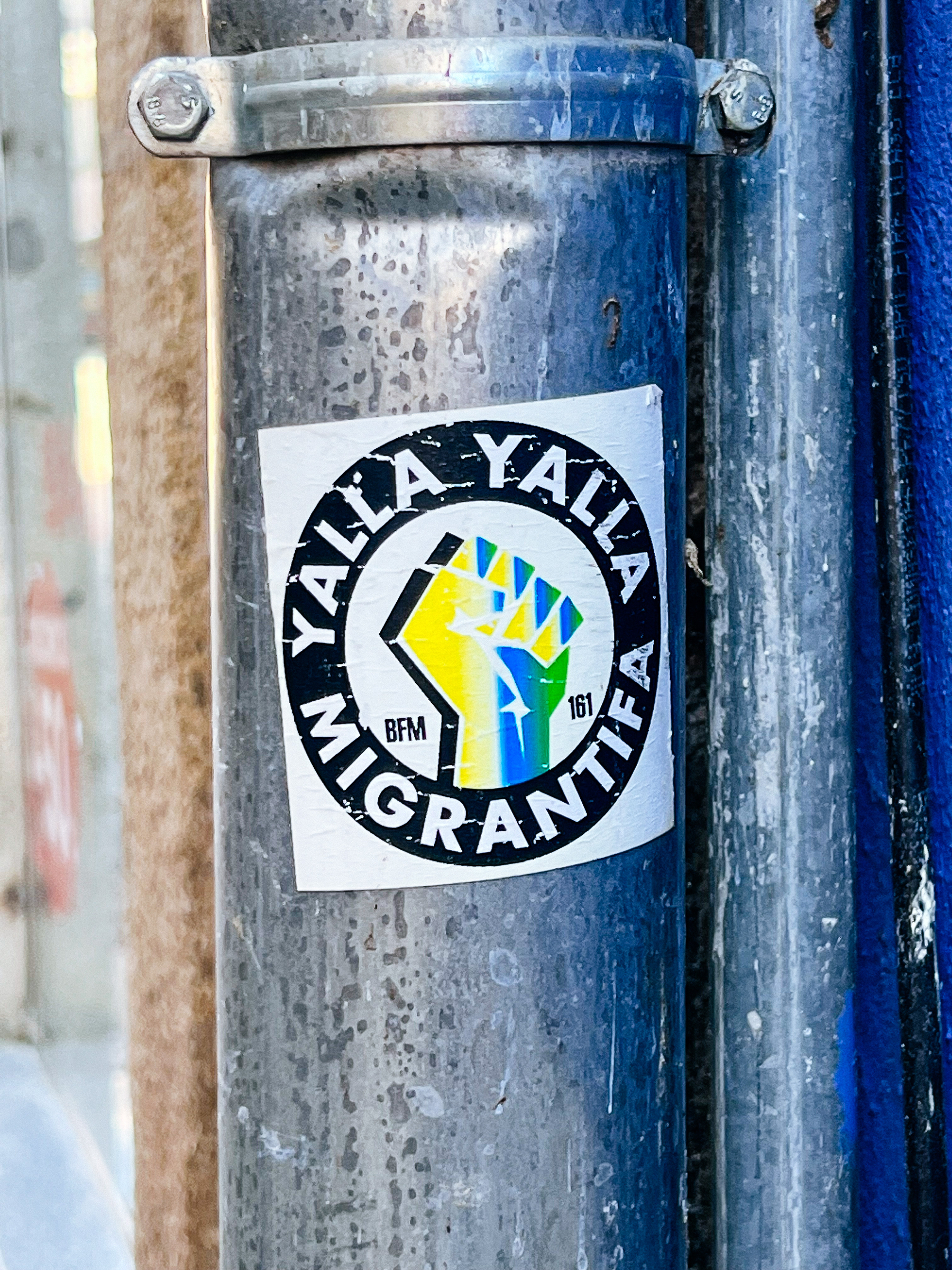 Sticker with the words “Yalla Yalla Migrantifa”, and a fist. 
