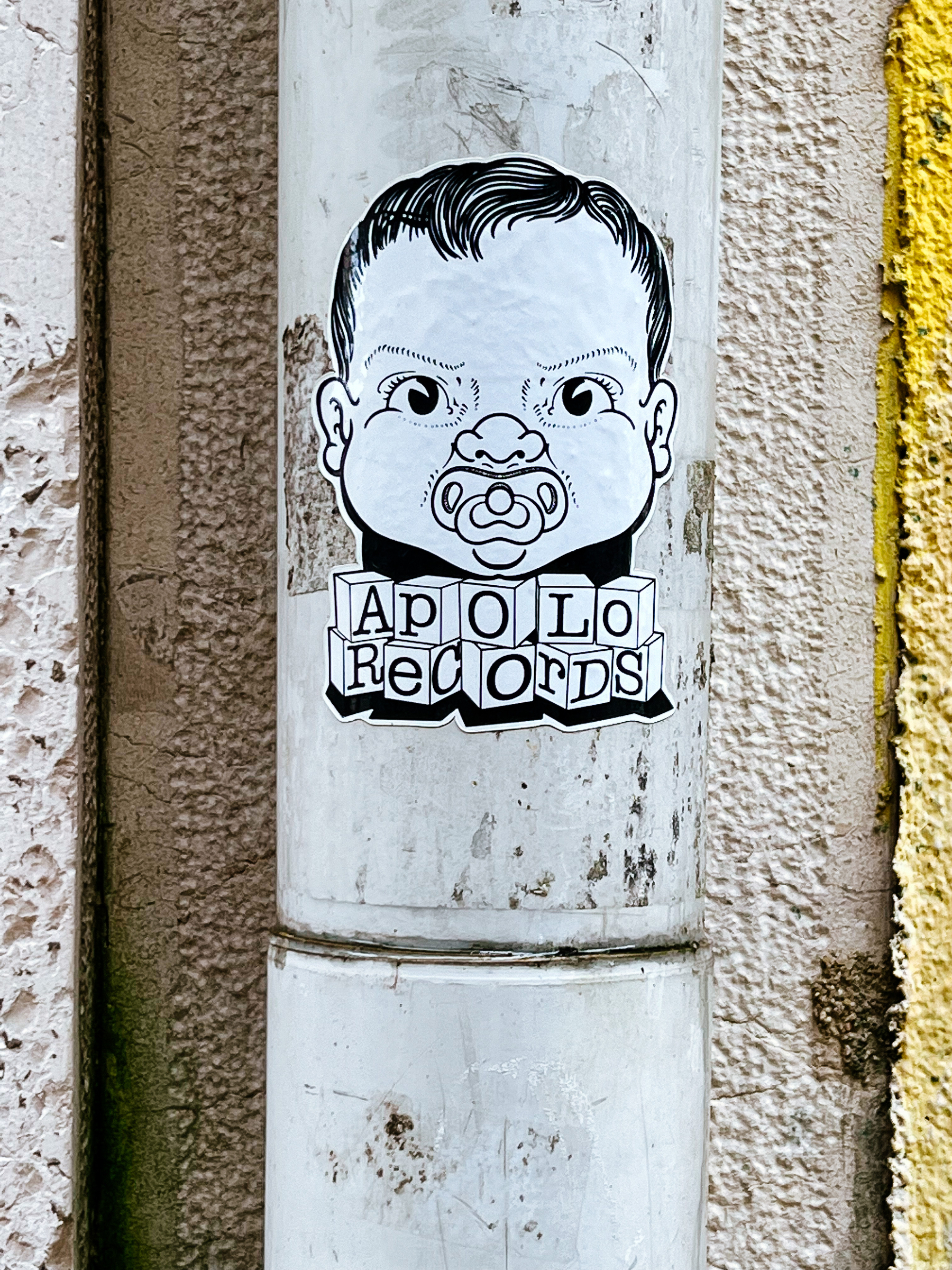 Sticker of a baby’s face with a pacifier, the words “Apolo Records” bellow it, in children’s cubes. 