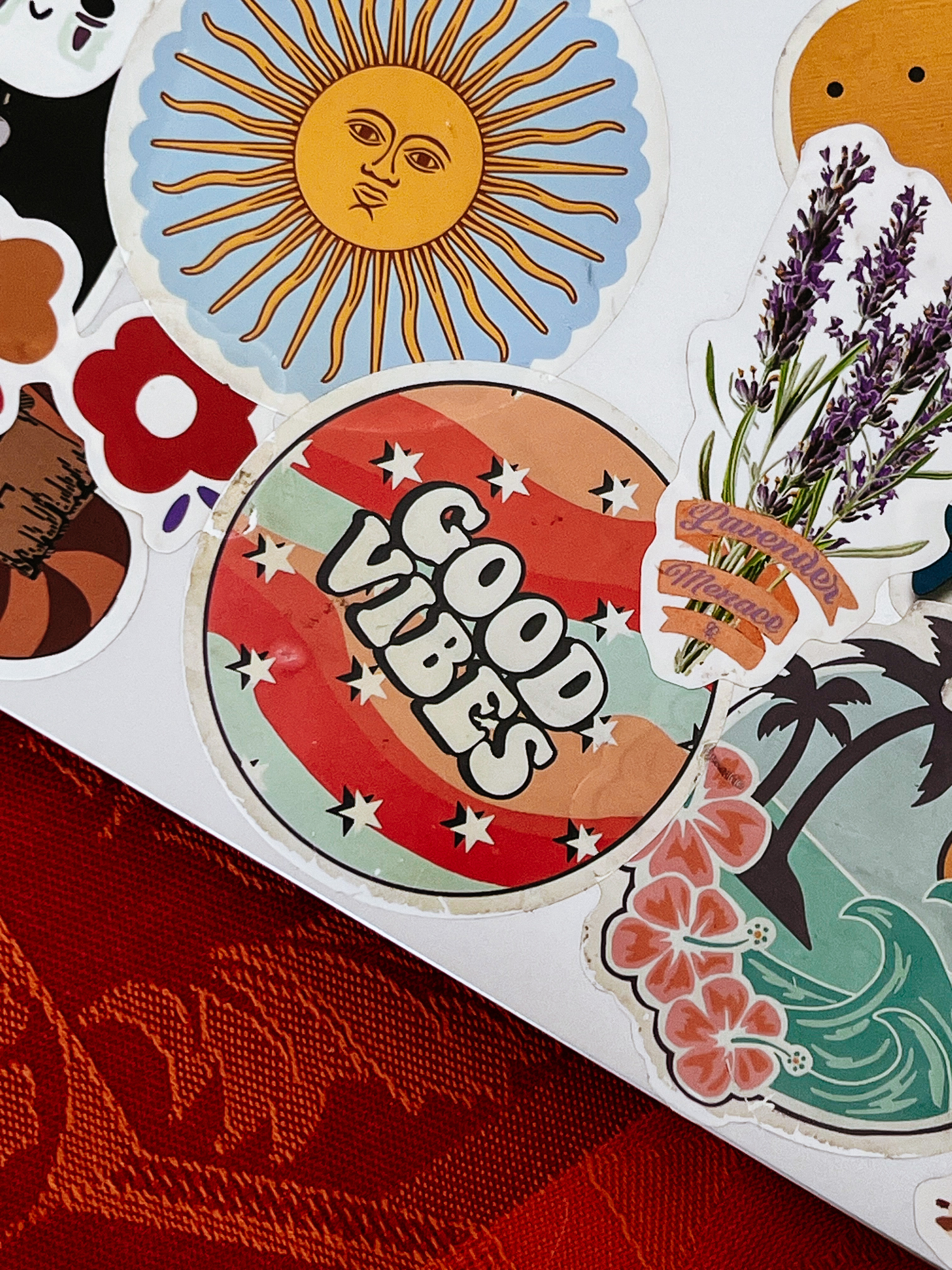 Stickers on a laptop. A sun, one with “Good Vibes” written on it, and “Lavender Menace”. 