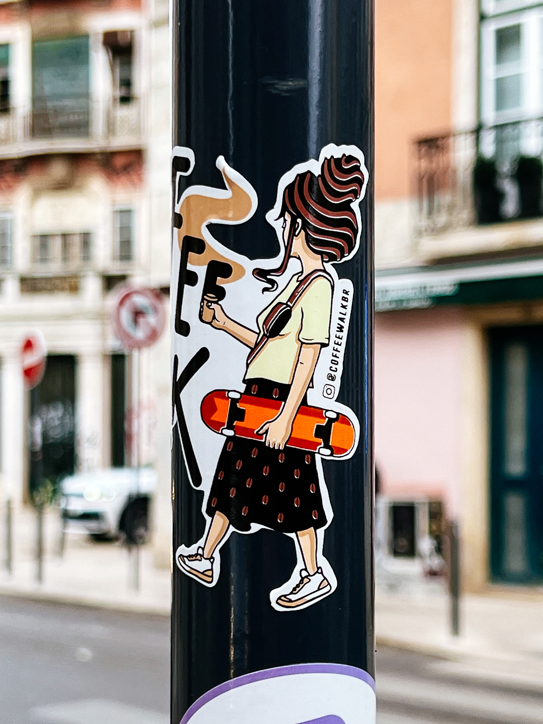 A sticker with a girl holding a skateboard and a coffee. 