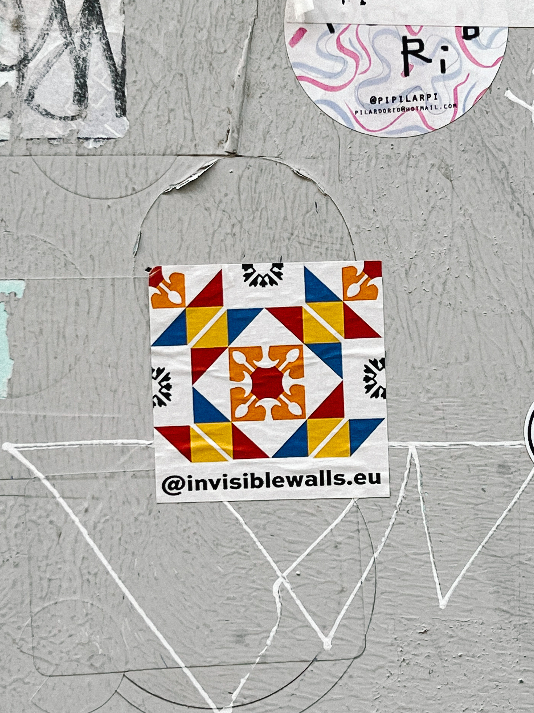 Sticker of what looks a bit like a tile, a colorful one, and “@invisiblewalls.eu” written at the bottom. 
