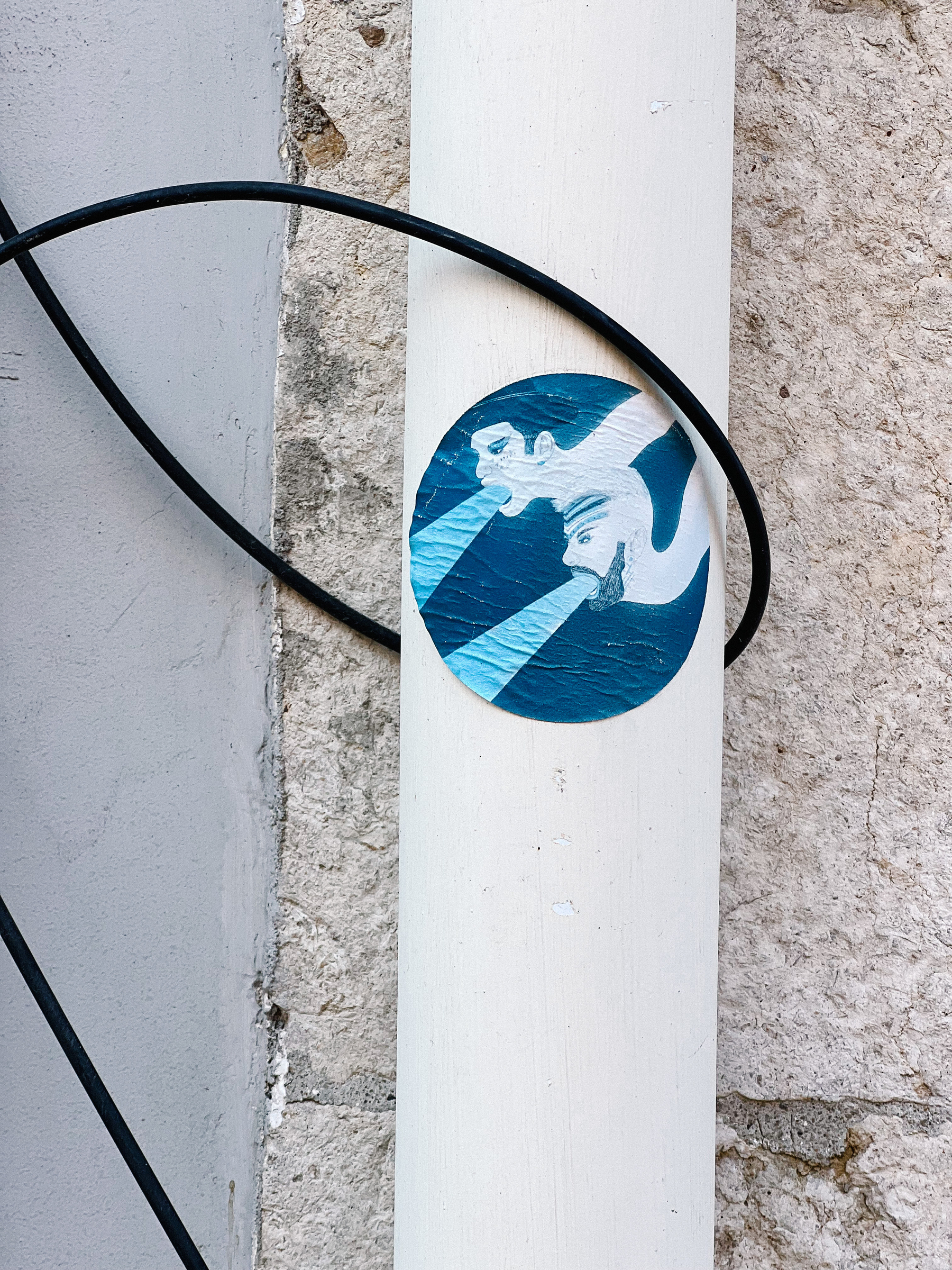 Sticker with two men’s heads, with blue light coming out of their mouths. 