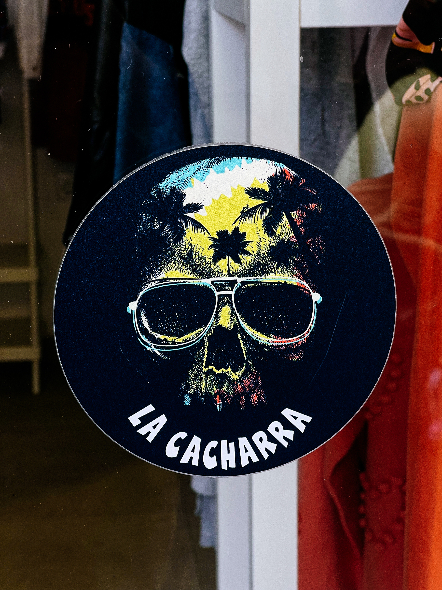 “La Cacharra”, and a skull wearing shades, with palm trees on the forehead. A sticker. 