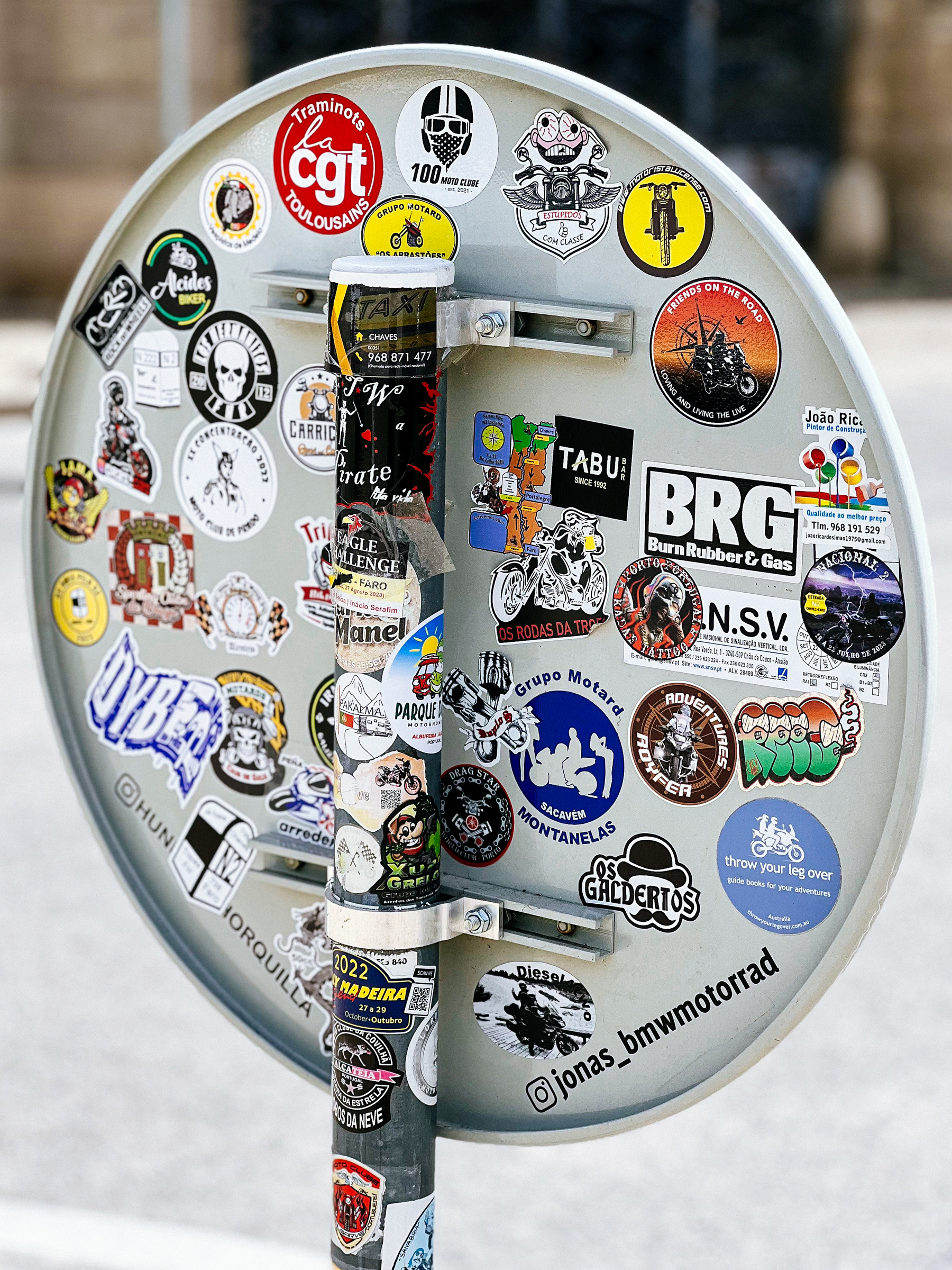 The back of a traffic sign with loads of stickers. 