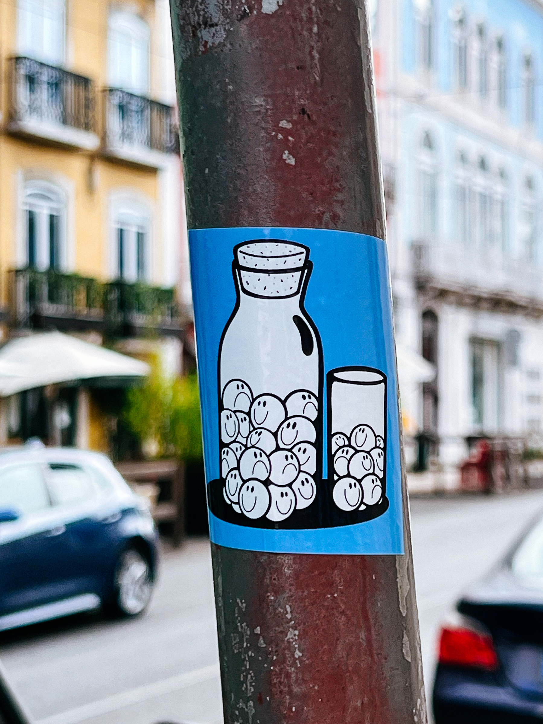 Sticker with an illustration of a bottle and a glass. Both have smiley and sad faces inside. 