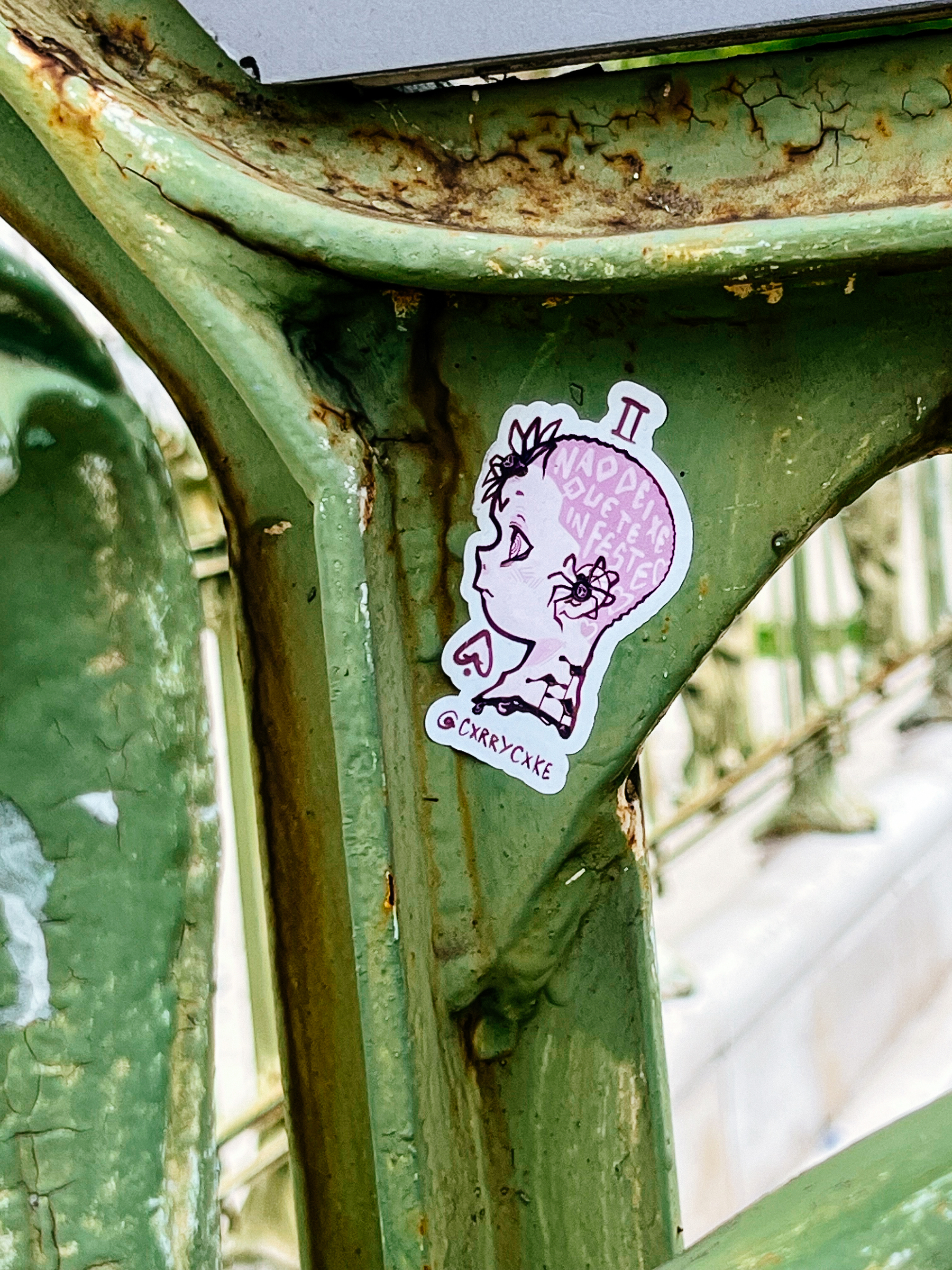 Sticker with a drawing of a girl’s face, profile view. Pink shaved hair. 
