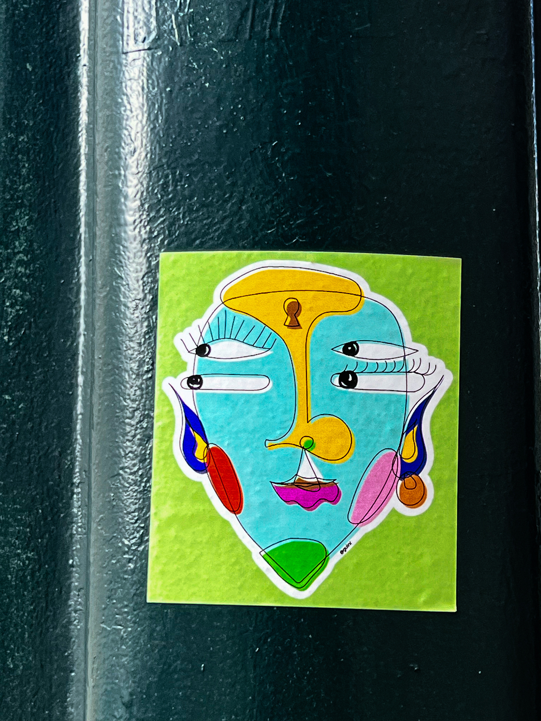 A very colorful sticker, depicting a face. It has four eyes. 