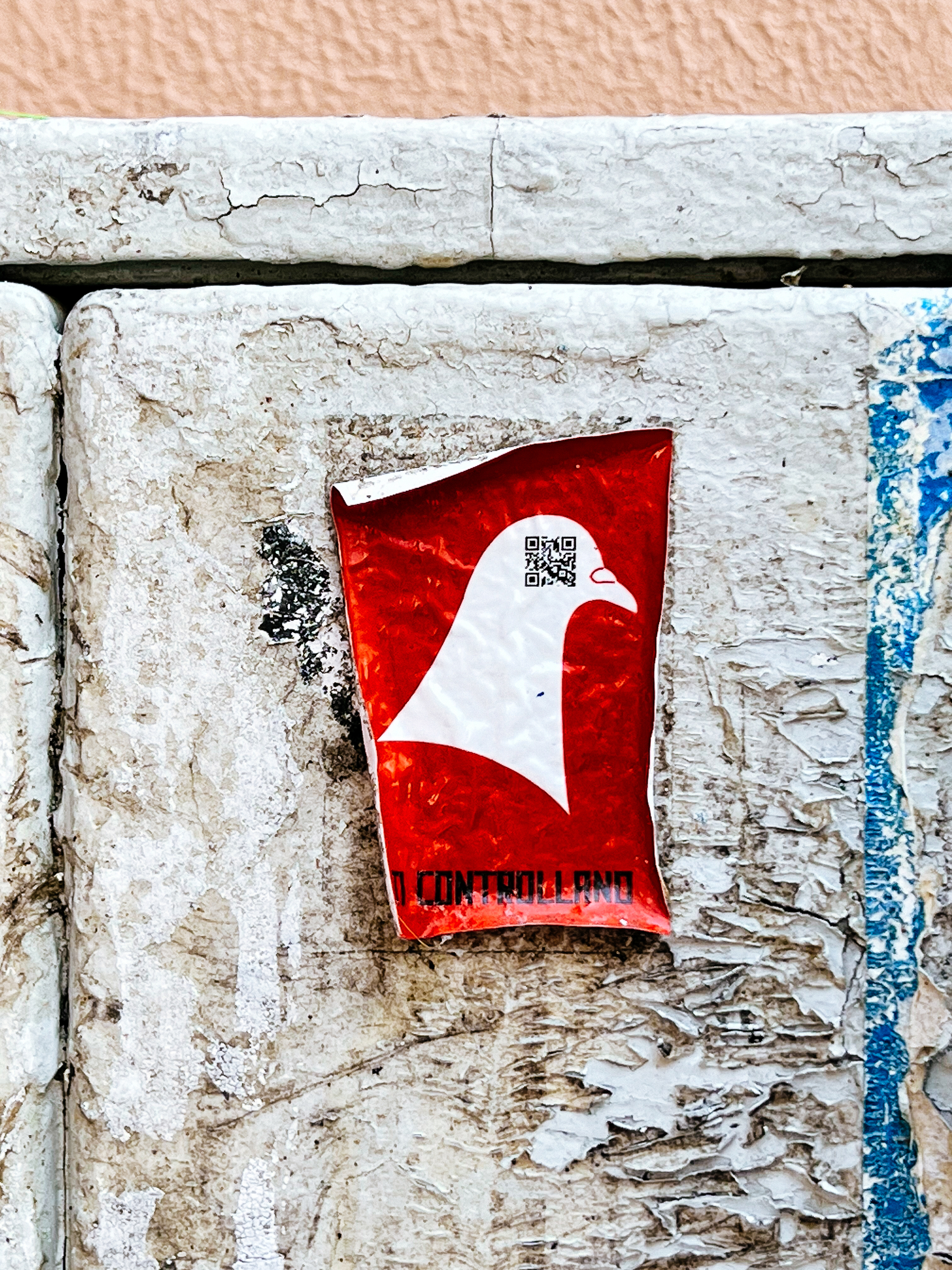 A red sticker with a pigeon’s head, with a QR code on it. 