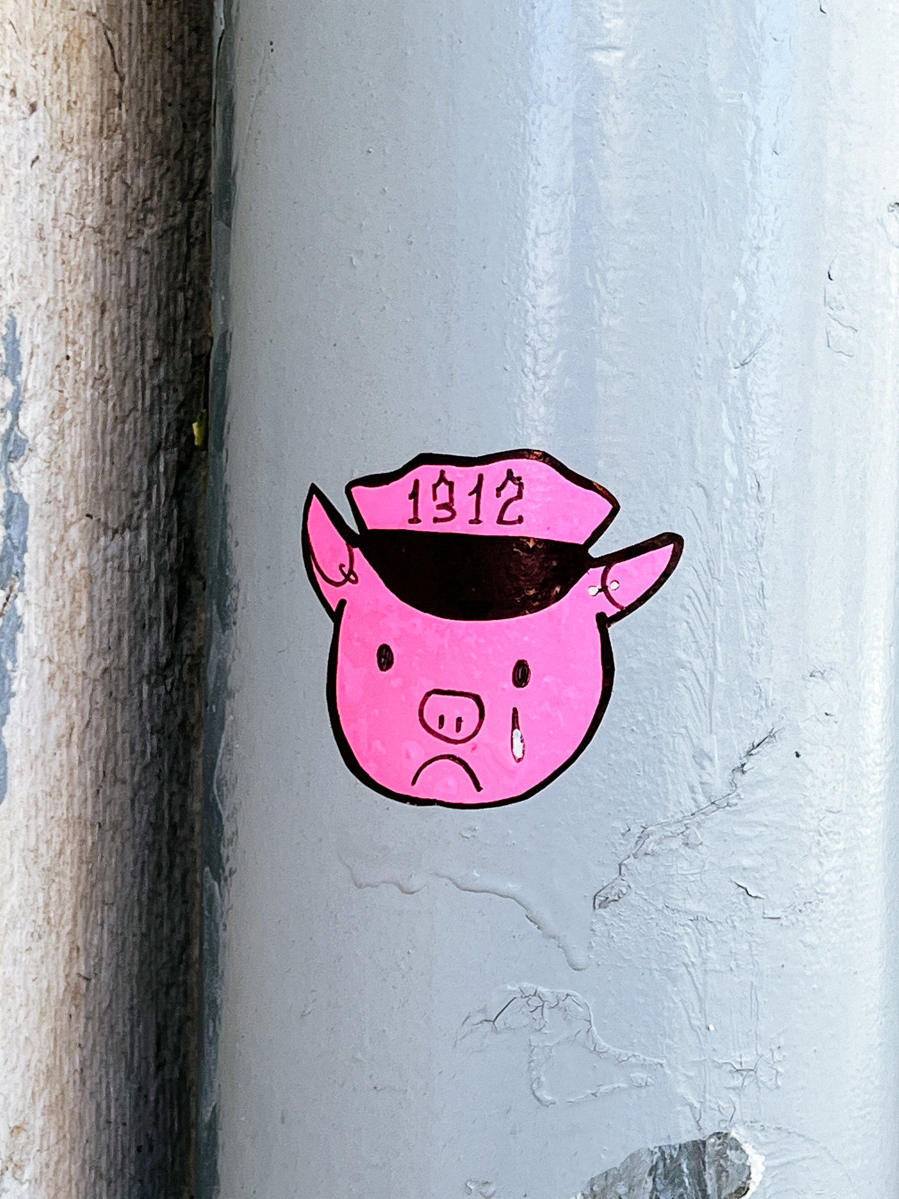 A very pink crying pig. 1312 on his cap. 