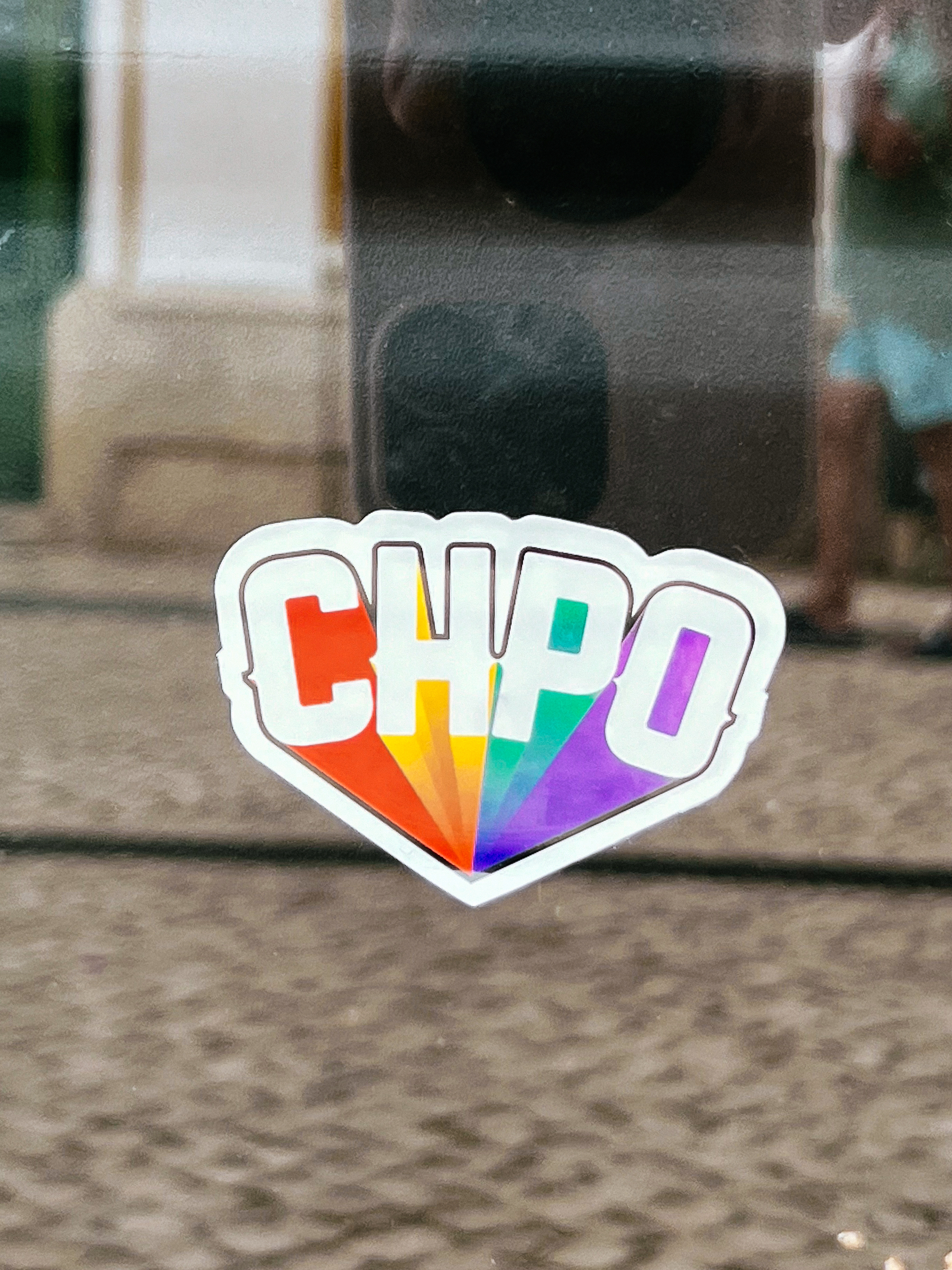“CHPO”, with rainbow colors going off into the distance. A sticker. On a window. 